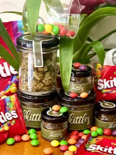 Bocaux de fleur de CBD Skittles mis en scène avec des bonbons
