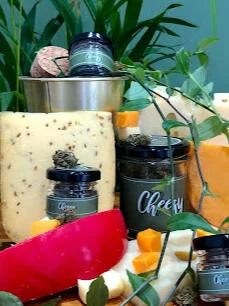 Bocaux de fleur de CBD Cheese posés entre des fromages